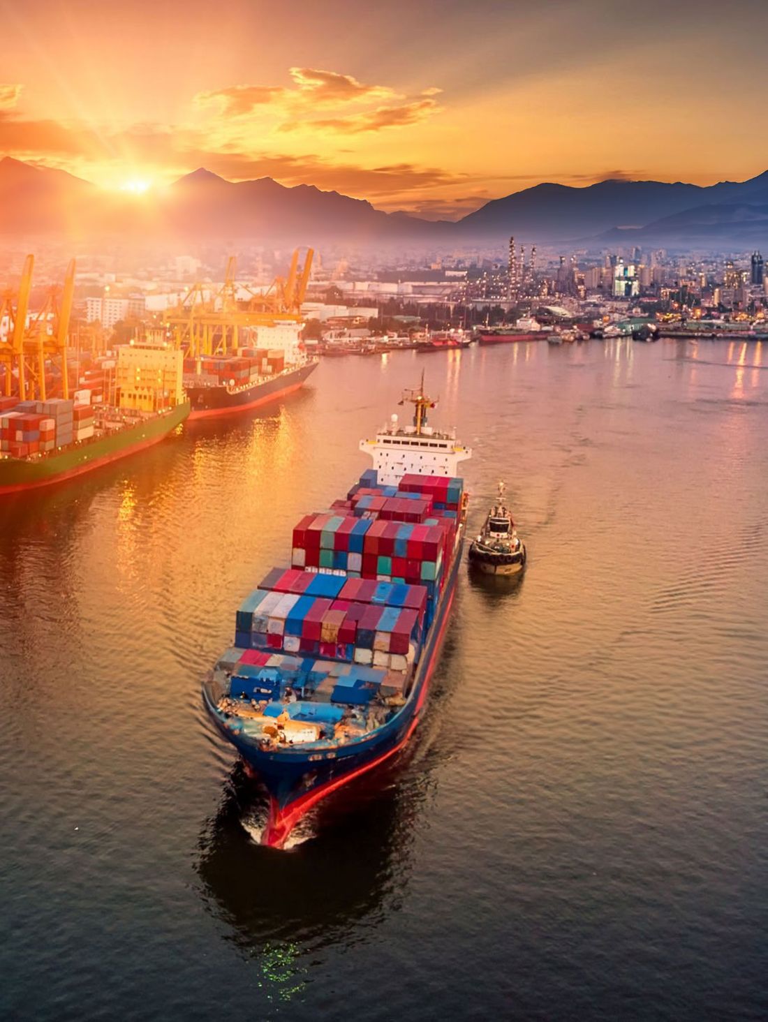 Container ship with a tugboat in a port at sunset